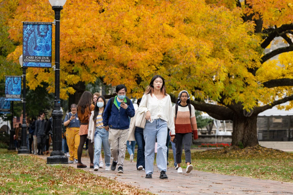 students walking across the campus with fall foliage in the background - Photo By: Phil Humnicky/Georgetown Univ.