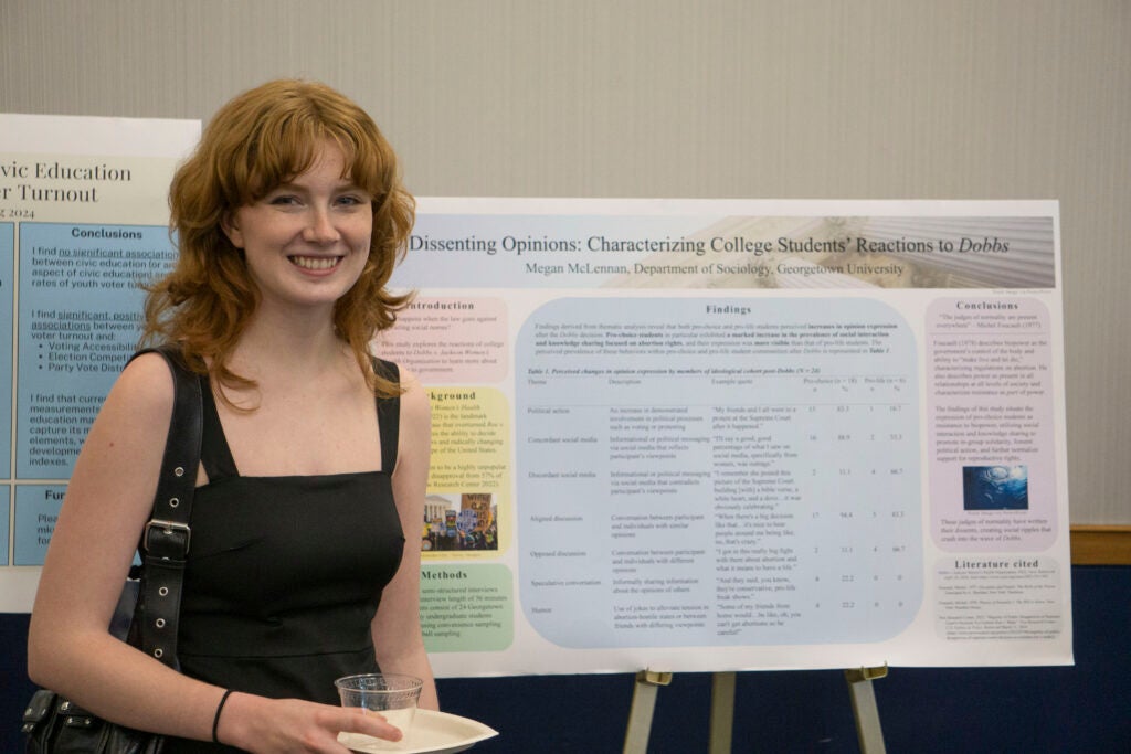 Senior Megan McLennan poses in front of their presentation