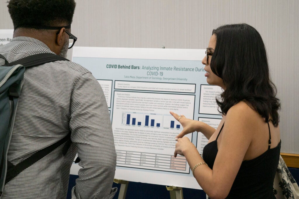 Senior Tahis Meza gestures at their presentation while discussing with Professor Corey Fields