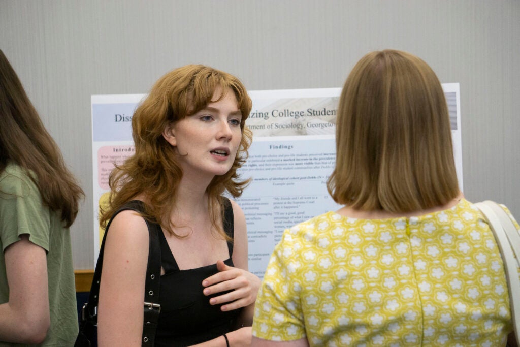 Senior Megan McLennan discusses their presentation with Professor Kristin Perkins