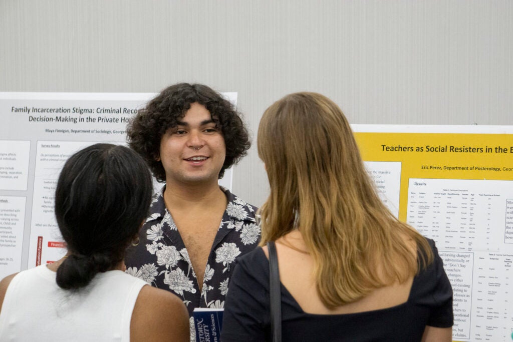 Senior Eric Perez discusses their presentation with senior Isabel Shepherd and another community member