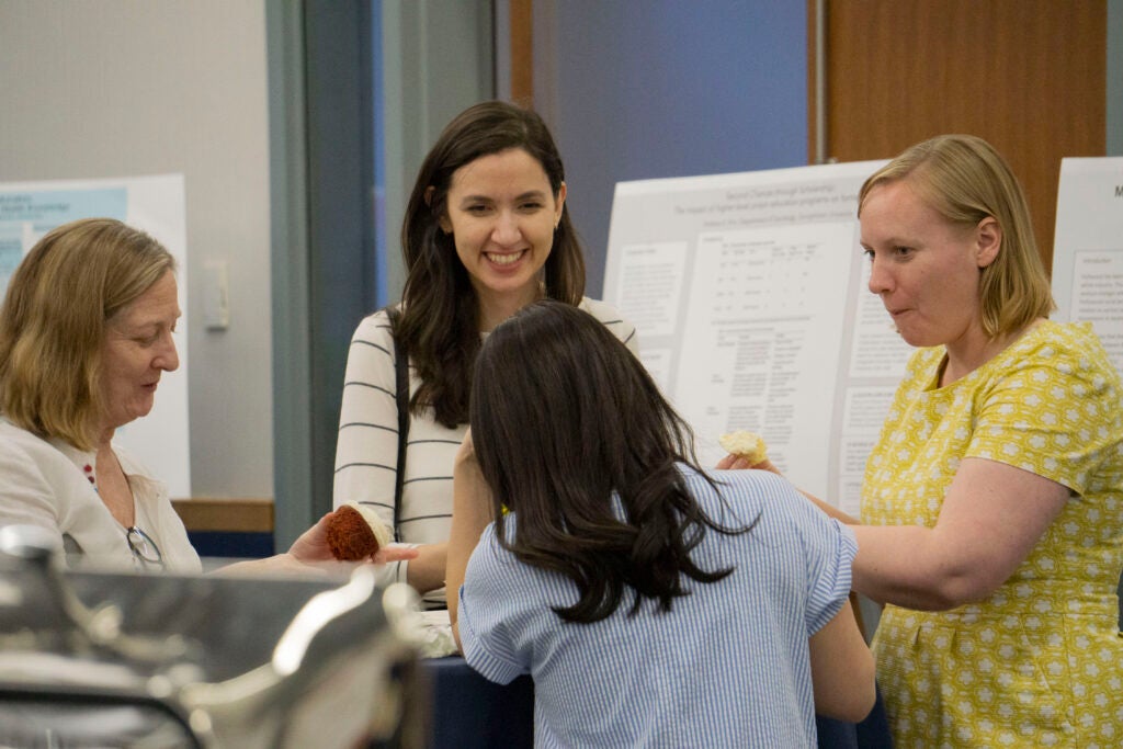 Professors Kathleen Guidroz, Gödze Güran, Becky Hsu and Kristin Perkins smile while talking with each other and eating