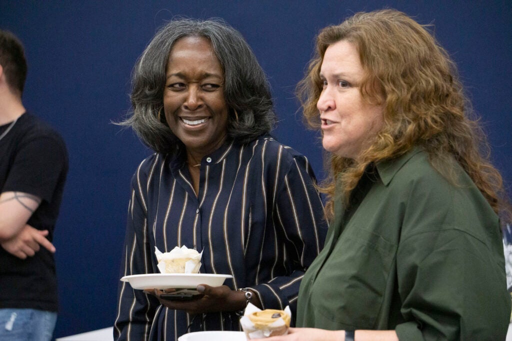 Professor Karolyn Tyson laughs while talking with a community member and holding a cupcake on a plate